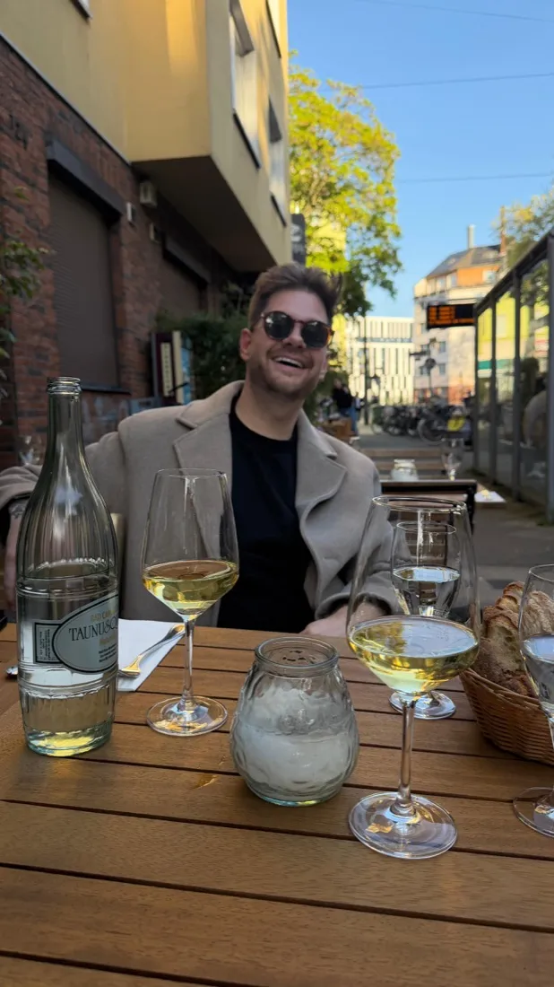 Julian with a glass of white wine at an outdoor table